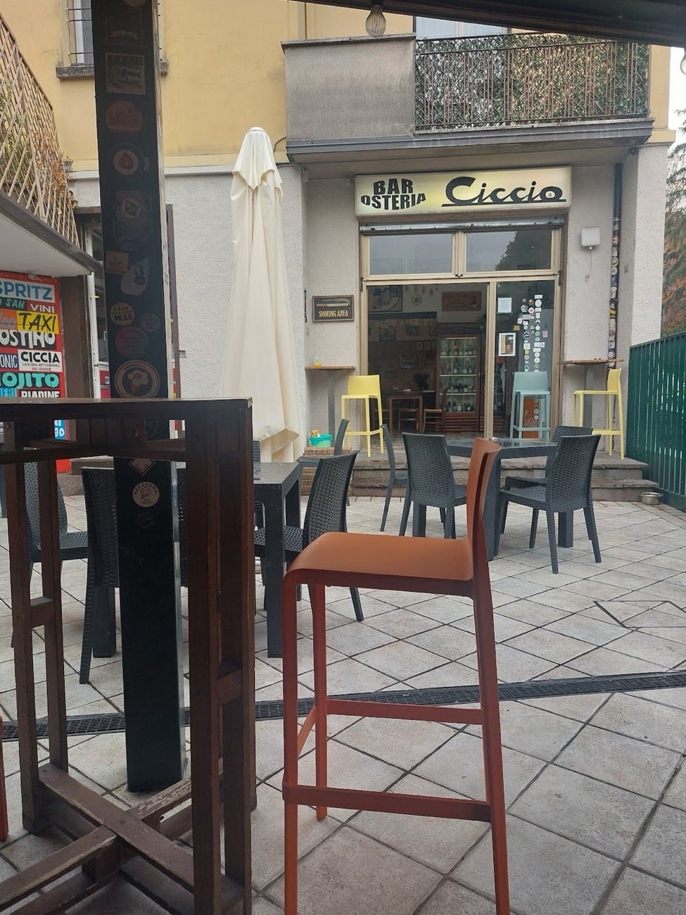 La vetrina e l'insegna del Bar Osteria Ciccio in Via San Mamolo, con i tavolini fuori